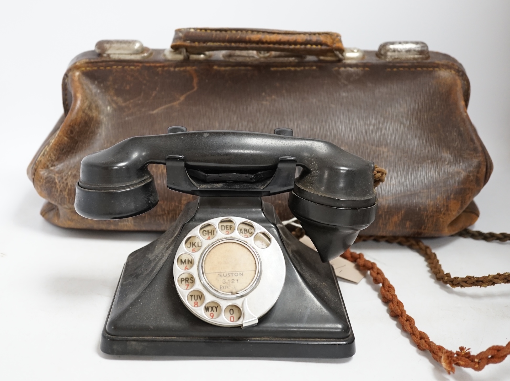 A brown leather Gladstone bag with a G.P.O. stamp and a pyramid-shaped black Bakelite telephone stamped G.P.O. Condition - poor